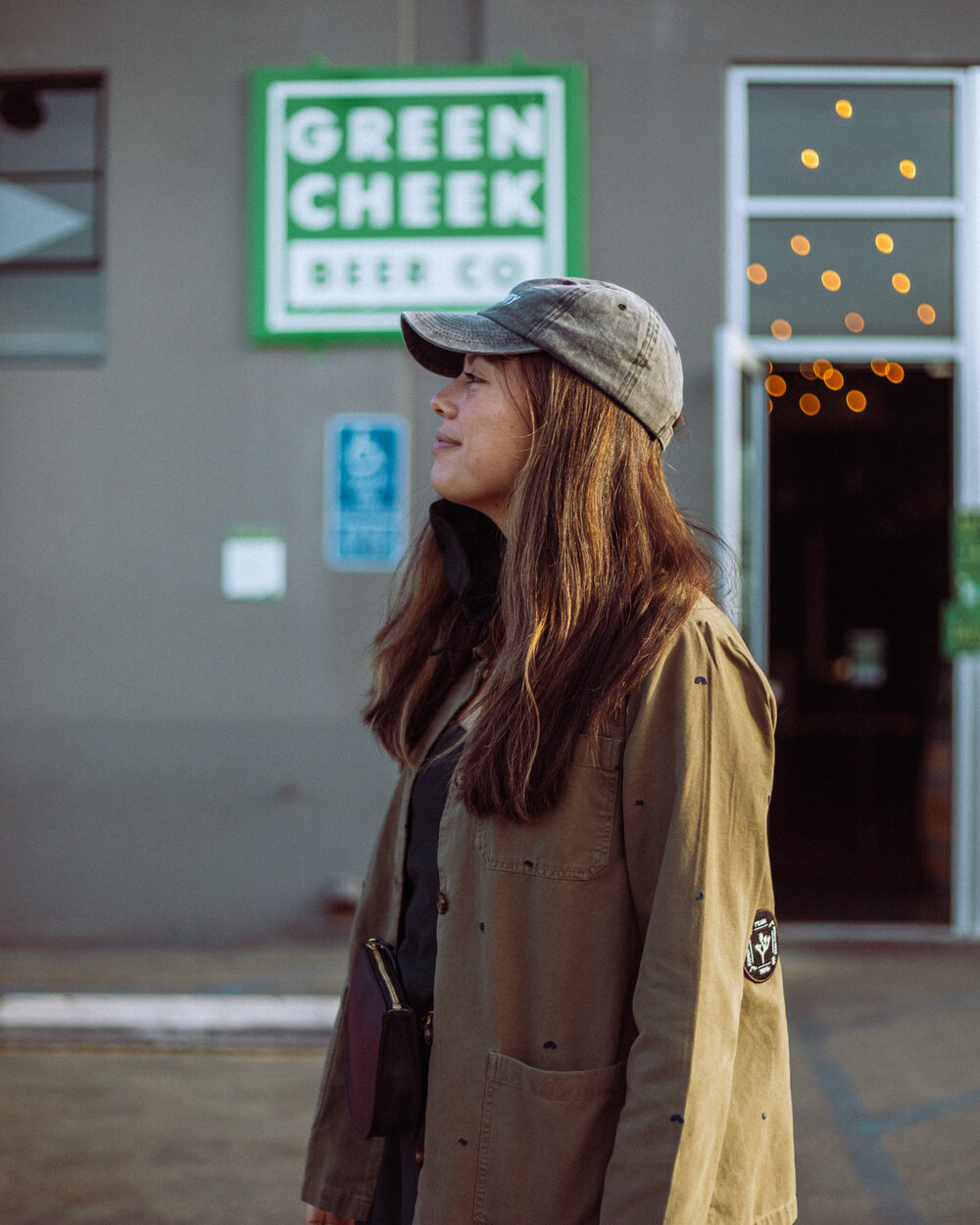 Rachel Off Duty: A Woman in a Green Jacket and Gray Hat Standing in Front of a Brewery