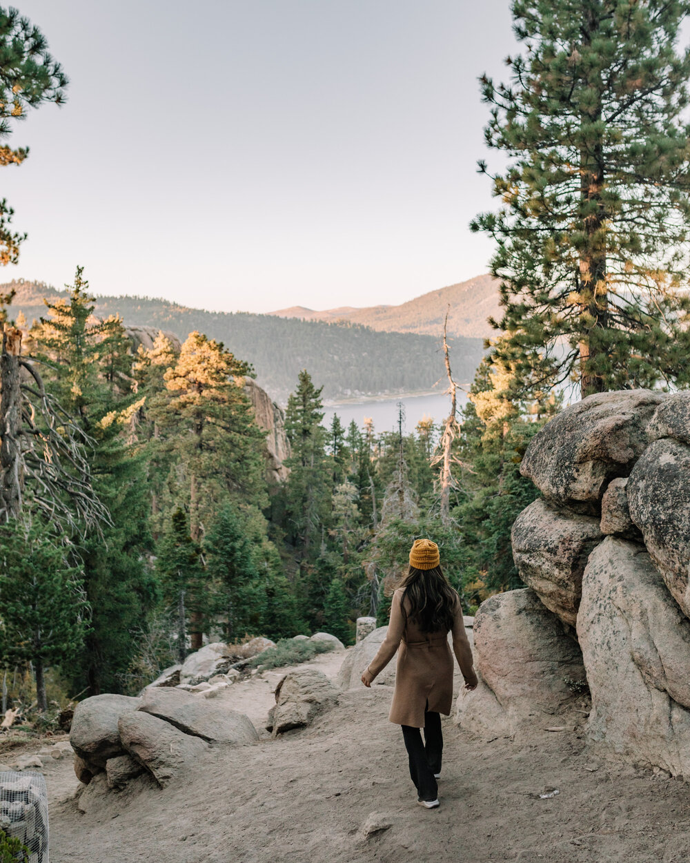 Rachel Off Duty: Woman in a coat hiking on a mountain with a view of a lake in Big Bear
