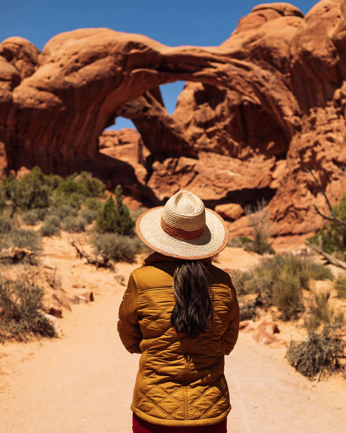 Rachel Off Duty: A Woman in a Yellow Jacket Admires the Double Arch in Arches National Park
